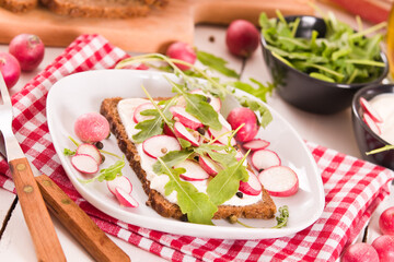 Rye bread with cottage cheese, radish and arugula.