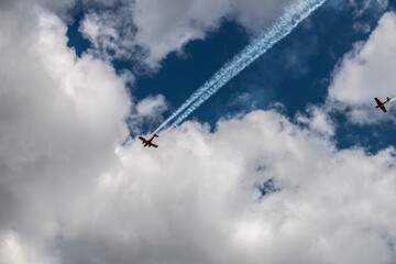 a beautiful plane makes a difficult turn leaves a white trail of flight against the background of the sky