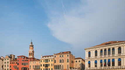 Fototapeta na wymiar Tower over colorful Venetian houses under blue sky, Venice, Italy