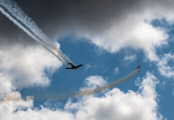 a group of combat aircraft perform complex aerobatics with a smoke launch against the sky