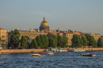 St. Petersburg, RUSSIA-July, 15, 2021: panoramic view of the Admiralty embankment with historical buildings and the golden dome of St. Isaac's Cathedral near the Neva River with boats on clear summer