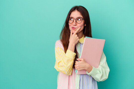 Young student caucasian woman isolated on blue background looking sideways with doubtful and skeptical expression.