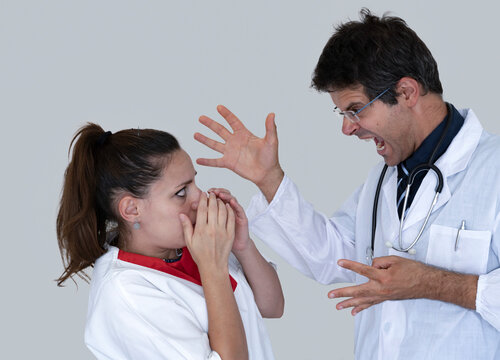 Doctor screams and yells at the poor scared and disconsolate nurse. Concept of bullying on nurses in healthcare.