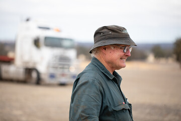 older man in workwear outdoors with prime mover in background