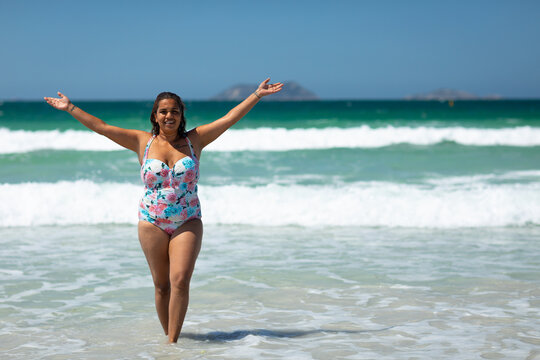 curvy young woman celebrating life in swimsuit at the beach