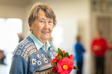 smiling elderly woman holding camellia flowers