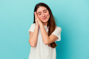 Young caucasian woman isolated on blue background yawning showing a tired gesture covering mouth with hand.