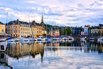 Honfleur harbor with church and water reflections under late day light, Normandy, France