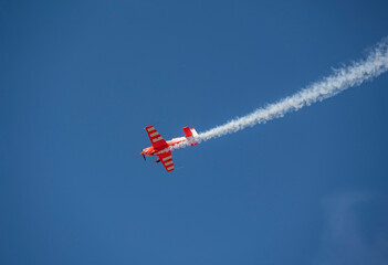 the red plane makes a difficult turn leaves a white trail of flight against the background of the...