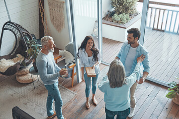 Top view of happy senior parents meeting young couple inside the house