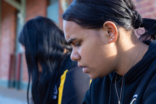 teenaged girl in profile with furrowed brow and another girl in background