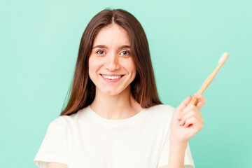 Young caucasian woman holding a toothbrush isolated on blue background