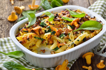 Nudelauflauf mit frischen Pfifferlingen und Blattspinat heiß aus dem Backofen serviert – Chanterelle pasta casserole with spinach leaves and cheese served hot from the oven