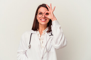 Young doctor caucasian woman isolated on white background excited keeping ok gesture on eye.
