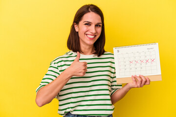 Young australian woman holding a calendar isolated on yellow background smiling and raising thumb up