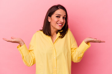 Young caucasian woman isolated on pink background confused and doubtful shrugging shoulders to hold...