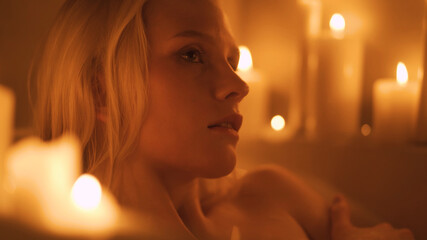 Relaxed woman washing hands in bath in slow motion. Sexy girl taking bathtub with bubbles and foam in slow motion. Top view of pretty lady enjoying in luxury bathroom with candles.