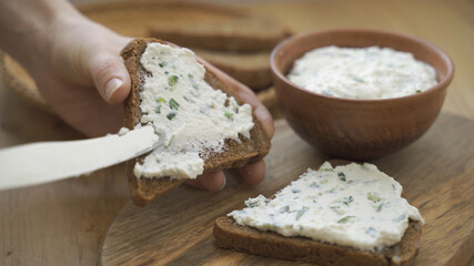 Spreading cream cheese with scallions on bread. Smear soft cheese on bread.