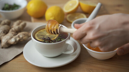 Put a teaspoon of honey in a Cup of hot tea with lemon. Close up.