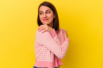 Obraz premium Young caucasian woman isolated on yellow background hugs, smiling carefree and happy.