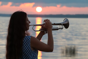 girl playing trumpet at sunset - obrazy, fototapety, plakaty