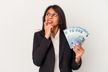 Young business latin woman holding bills isolated on white background relaxed thinking about something looking at a copy space.