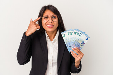 Young business latin woman holding bills isolated on white background showing a disappointment gesture with forefinger.