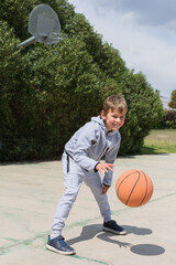 Stylish young boy, teenager is playing with ball, outdoors