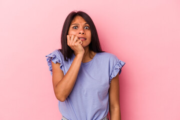 Young latin woman isolated on pink background biting fingernails, nervous and very anxious.