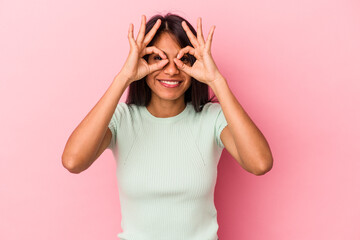 Young latin woman isolated on pink background showing okay sign over eyes