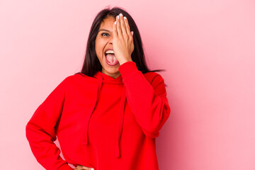 Young latin woman isolated on pink background having fun covering half of face with palm.
