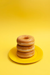 Glazed doughnuts on yellow background