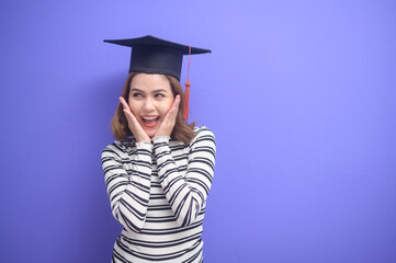 Portrait of young woman graduated over blue background