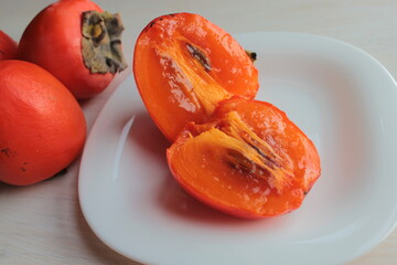 Ripe and juicy persimmon cut on a white plate.