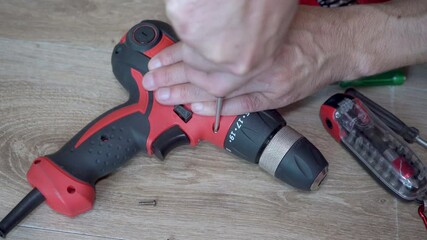 disassemble an electric screwdriver,man unscrews a screwdriver electric drill, repairing household power tools