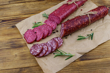 Salami sausages on craft paper on a wooden table