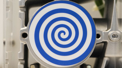 Close up of rotating white flat circle with bright blue spiral that creating hypnotic effect. HDR. Unusual robot with automated spinning hypnotic circle.