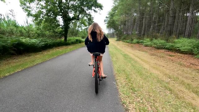 cute young girl mountain biking in forest paths