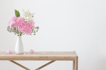 white and pink flowers in white vase on wooden shelf