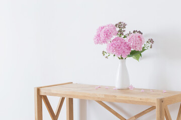 pink   hydrangea in white vase on wooden shelf  on background white wall