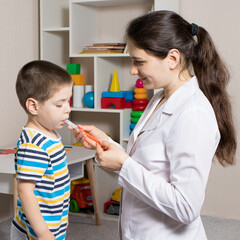 The pediatrician or nurse gives the child syrup in a measuring syringe. Treatment of cough, temperature in children. Paracetamol or ibuprofen for toddlers and preschoolers in pediatrics