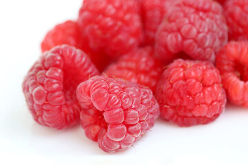 Red raspberry on white background. Pile of ripe berries close up, summer crop