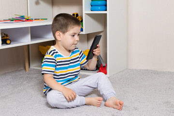 A small child and a mobile phone in the children's room with place for text. Cartoons and...