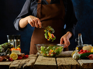 Greek salad Restaurant vitamin vegetarian dish. Many beneficial ingredients are used. The chef mixes the salad with a spoon in a large glass salad bowl.