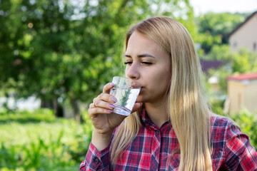 girl drinks water from a glass, outdoors.