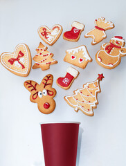 Top view of homemade Christmas gingerbread cookies decorated with red and white colored royal icing and different shapes on white background. Festive dessert and holidays celebration concept.