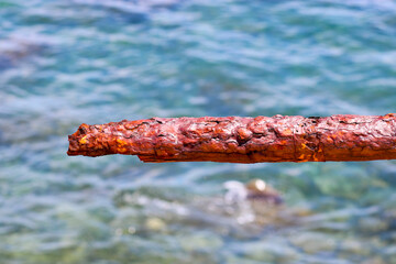 Remains of a rusted handrails on an abandoned waterfront on a blurred background of azure sea...