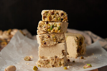 Organic halva with pistachios on a wooden surface. Traditional middle eastern sweets. Jewish, turkish, arabic oriental national dessert. Turkish delight concept. Natural vegan product. Copy space.