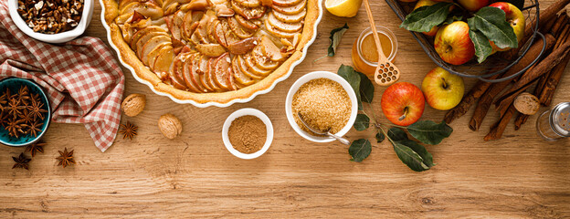 Cooking Thanksgiving autumn apple pie with fresh fruits and walnuts on wooden background, top view. Banner.