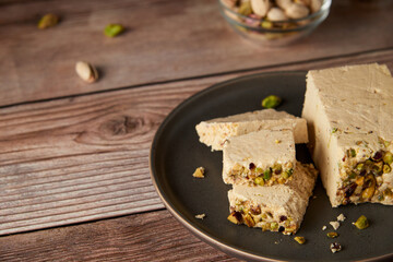 Organic halva with pistachios on a wooden surface. Traditional middle eastern sweets. Jewish, turkish, arabic oriental national dessert. Turkish delight concept. Natural vegan product. Copy space.